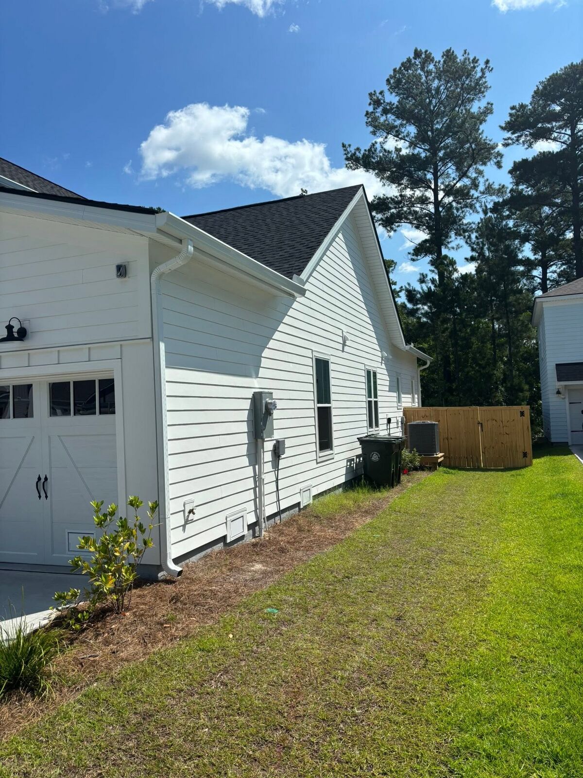 Seamless gutters and downspout on a white siding home and garage