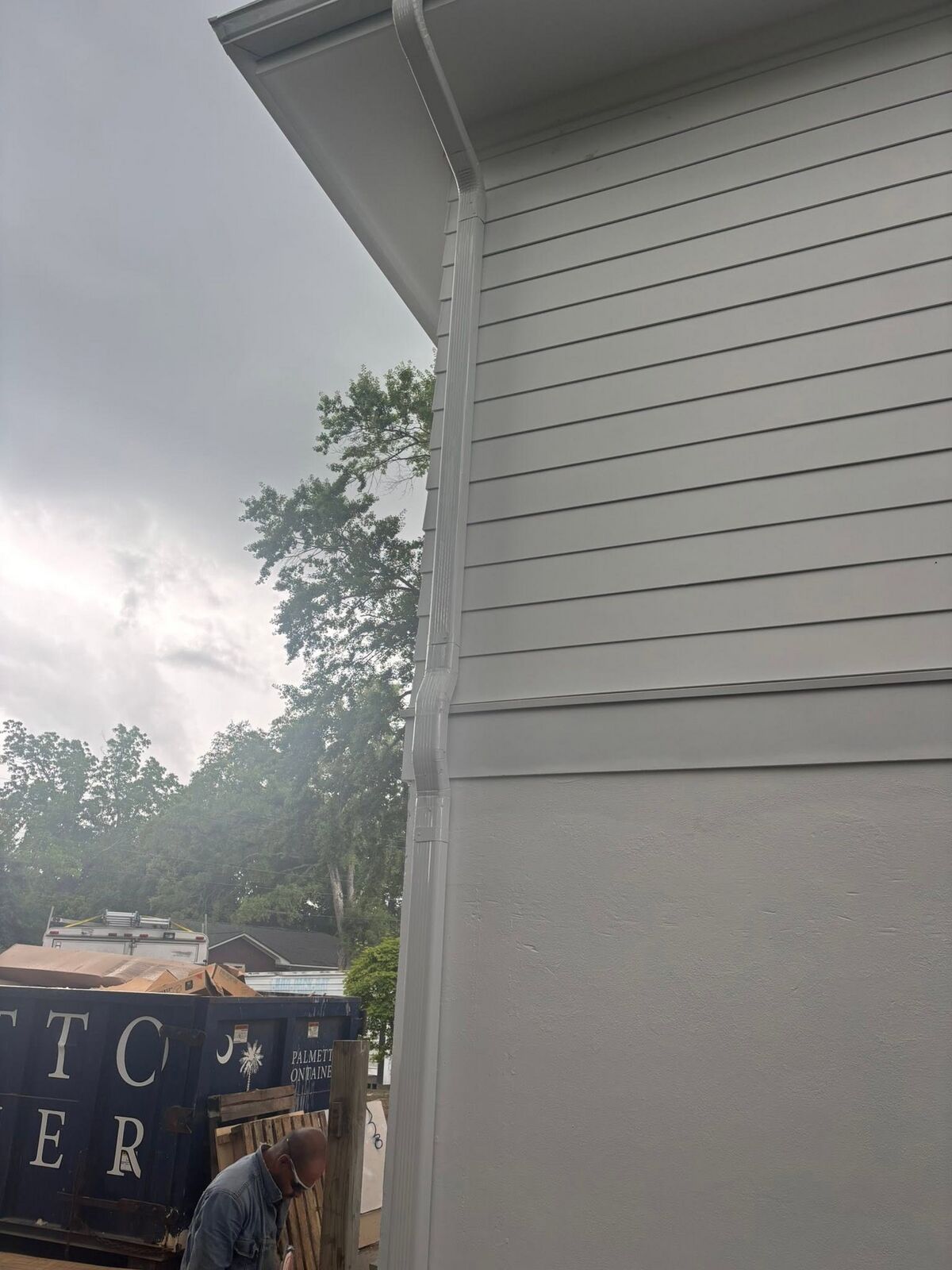Crisp corner miter and downspout on a gray new-build exterior