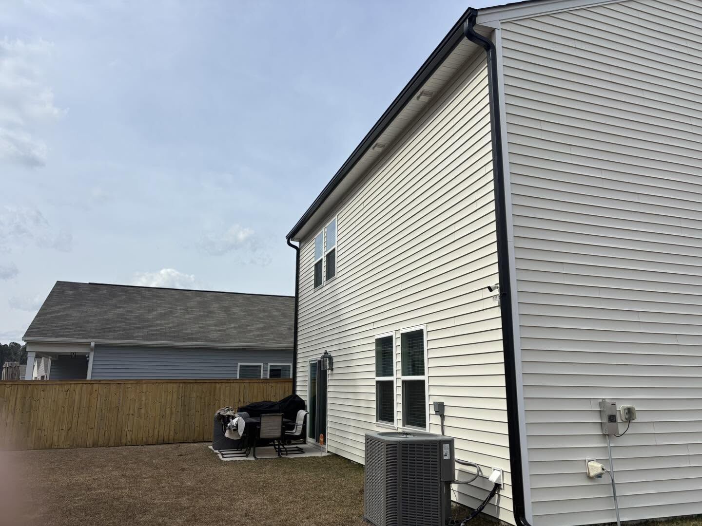 Seamless gutters with dark trim on a tan two-story home